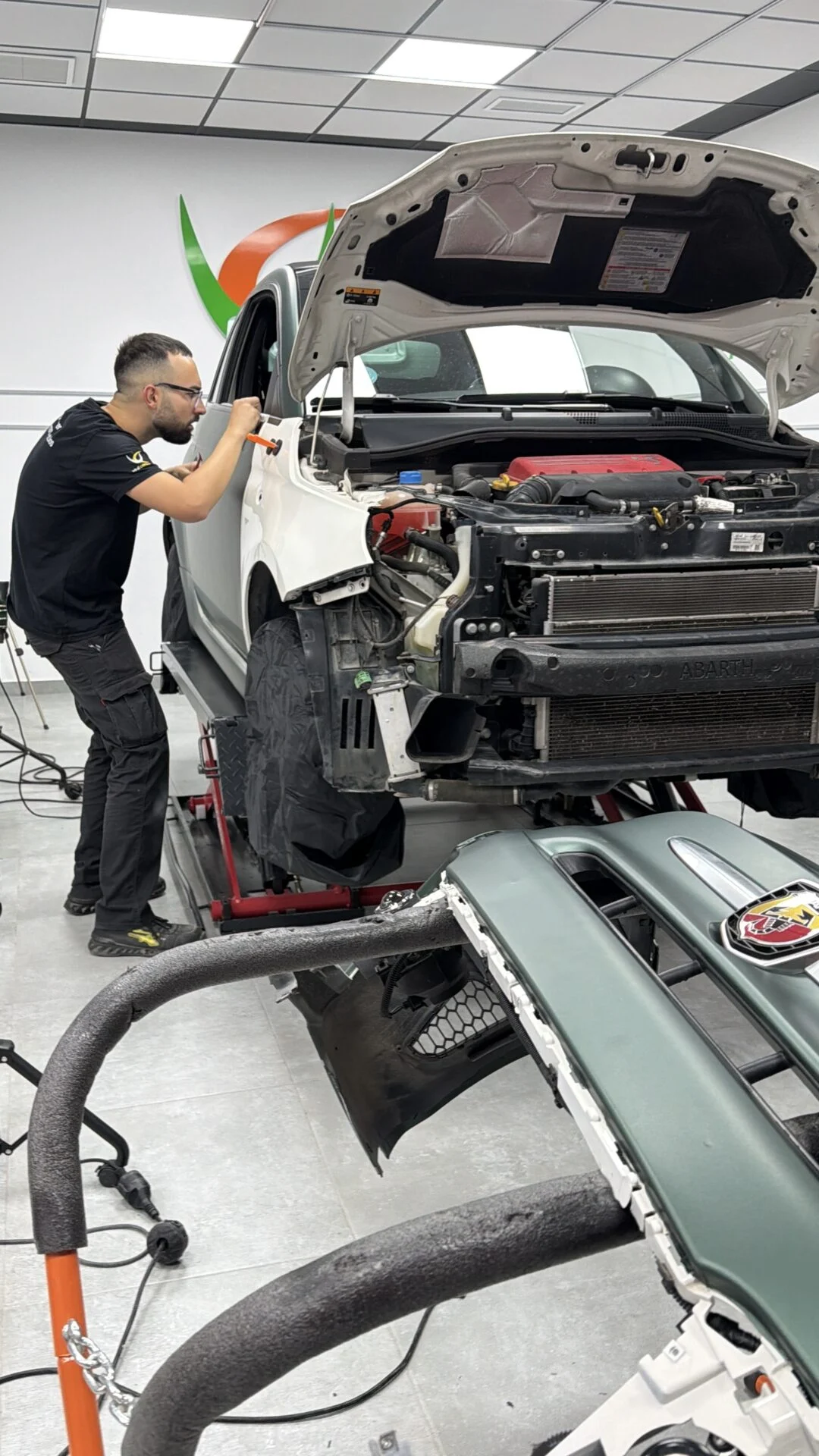 Técnico de VinilCenter instalando vinilo verde militar mate en un Abarth 595 con las piezas desmontadas