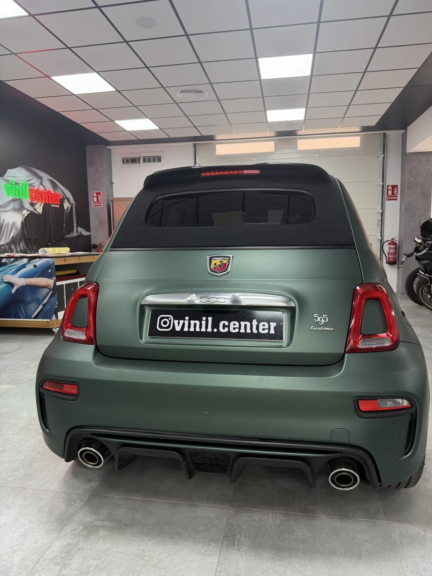 Trasera del Abarth 595 Turismo cabrio en verde militar mate con techo y capota negros de contraste